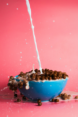 Chocolate breakfast cereals and plant milk poured into the bowl, concept of breakfast and morning, selective focus, dynamic pictureの写真素材