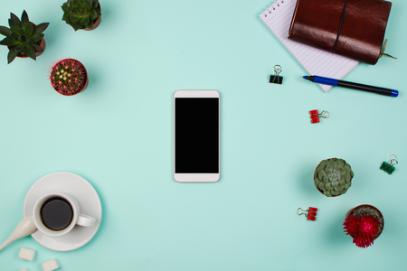 Business flatlay with smartphone with black copyspace screen, succulents and cactuses and other business accessories. Mint color background. Top viewの写真素材