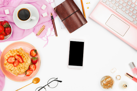 Beautiful flatlay arrangement with cup of coffee, hot waffles with cream and berries, laptop, smartphone with copyspace and other accessories: concept of busy morning breakfast, white background.の写真素材
