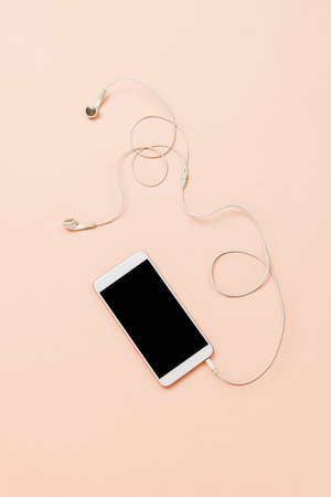 White smartphone with black copyspace and white headphones on a pastel background. Top view, flatlayの写真素材