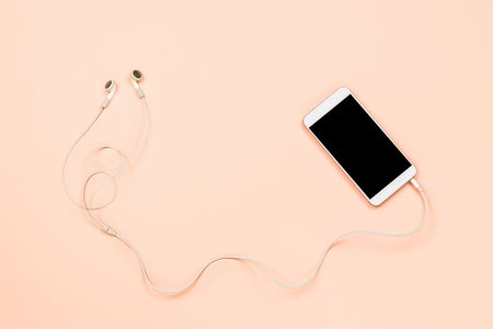 White smartphone with black copyspace and white headphones on a pastel background. Top view, flatlayの写真素材