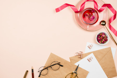 Various stationary accessories on pastel background with cup of tea and smartphone with black...