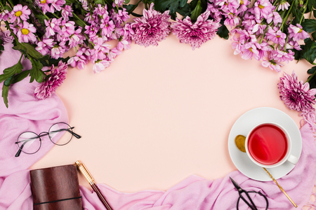 Flatlay frame arrangement with pink chrysanthemum flowers, hibiscus tea, pink scarf, glasses and notebook, pastel background. Copyspaceの写真素材