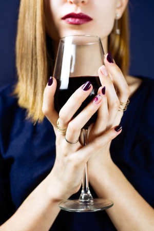 Faceless portrait of a young woman holding a glass of red wine. Selective focus.の写真素材