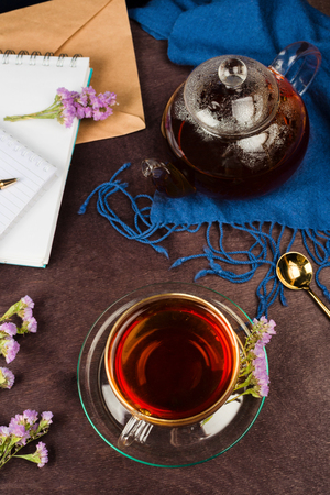 Above shot of cup of tea, teapot, violet wildflowers, spoon and notebooks. Concept of writing, planning or studyingの写真素材