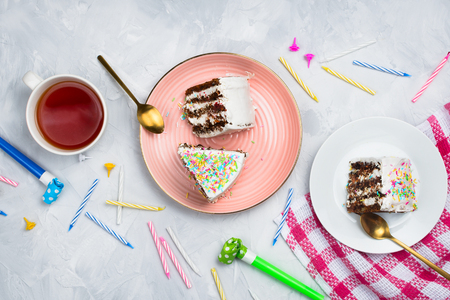 Vegan carrot cake pieces with cup of tea and birthday decorations and supplies, flatlay, cement backgroundの写真素材