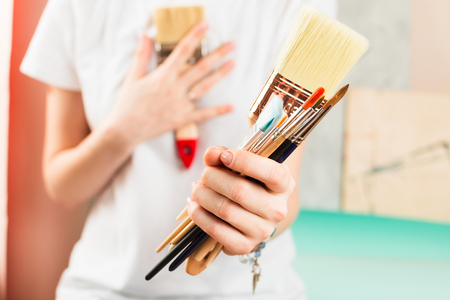 Closeup of woman holding painting brushes in her hand, selective shallow focusの写真素材