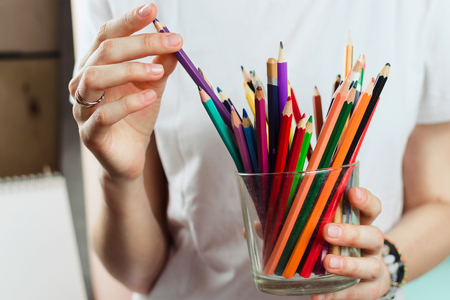 Closeup of woman holding colorful pencils, selective shallow focus.の写真素材