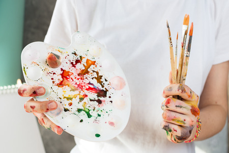 Closeup of woman holding painting brush and palette in her hands, selective shallow focusの写真素材