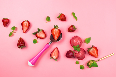Fresh organic strawberries, sorbet balls, mint leaves and ice cream spoon on pink, pastel background, flatlayの写真素材