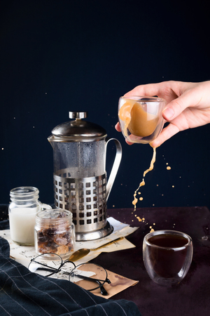 Closeup of coffee, french press, glasses and women hand holding cup with splashing beverage, selective focusの写真素材