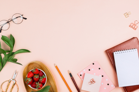 Business flatlay mockup with strawberries on a wooden tray, notebooks, glasses, ruscus branches and other accessories on pastel background with copyspaceの写真素材
