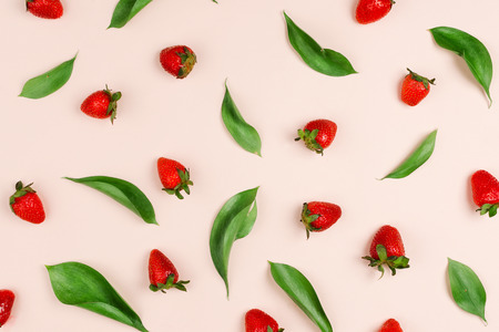 Beautiful flatlay pattern of ruscus leaves and fresh organic strawberries on a pastel backgroundの写真素材