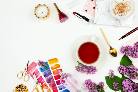 Lifestyle and business mockup flatlay with cup of tea, lilac, notebook, perfume and other accessories on white with copyspaceの写真素材