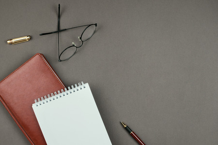 Stylish minimalist mockup with notebook, planner, glasses and pen on grey background on copyspace