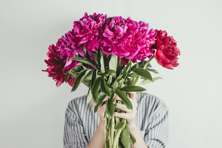 Faceless portrait of woman holding bouquet of violet and purple flowers, selective focusの写真素材