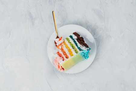 Flat lay of rainbow vegan cake piece on grey background