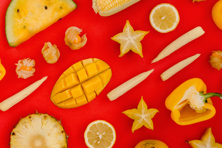 Flatlay of various yellow and orange fruits and vegetables knolled on redの写真素材