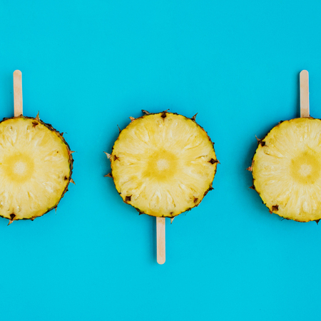 Circles of pineapple on a wooden ice cream sticks, square