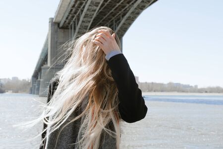 Lifestyle portrait of young adult female on a beach with flying hair, selective focus