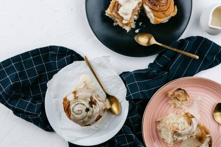 Flatlay of homemade cinnamon rolls with cream and tea on white cement backgroundの写真素材