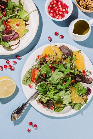 Flatlay of two citrus salad plates  with pomegranate seeds, nut and olive oil on blue backgroundの写真素材