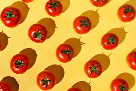 Flatlay of fresh red ripe tomatoes knolled on yellowの写真素材