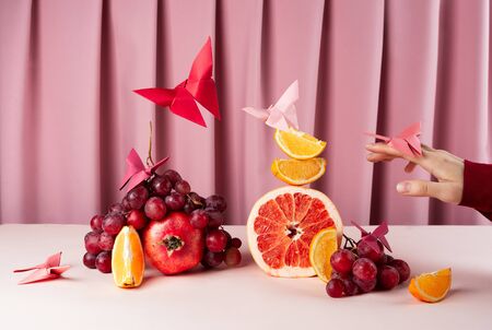 Various fruits on pink table with origame paper butterflies, selective focusの写真素材