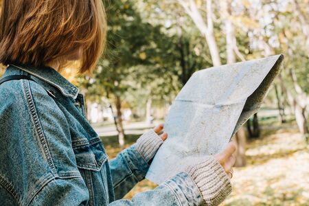 Lifestyle portrait of young adult female in a forest or park holding map in her hands, selective focusの写真素材