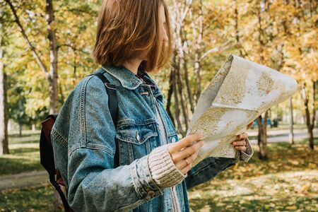 Lifestyle portrait of young adult female in a forest or park holding map in her hands, selective focusの写真素材