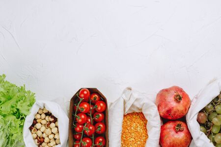 Flatlay of zero waste sustainable food shopping: grapes, tomatoes, peas, greens, hazelnuts etc in produce bagsの写真素材