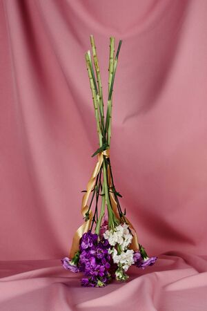 A flower bouquet standing upside down on a table covered with pink clothの写真素材