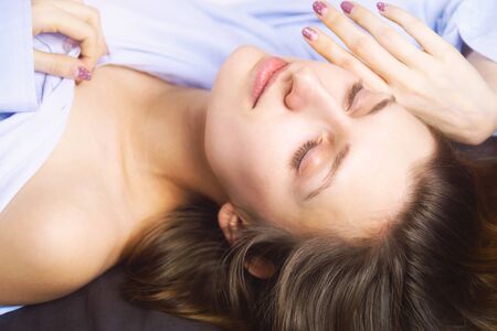 Close up of young beautiful woman in blue lying in bed.の写真素材
