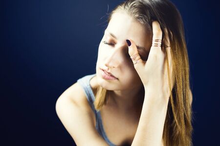 Portrait of young adult white woman with her eyes closed covering one side of her faceの写真素材