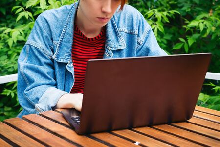 Closeup portrait of young adult female freelancer working on her laptop outsideの写真素材