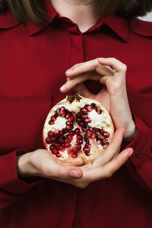 Closeup of woman's hands holding half of pomegranateの写真素材