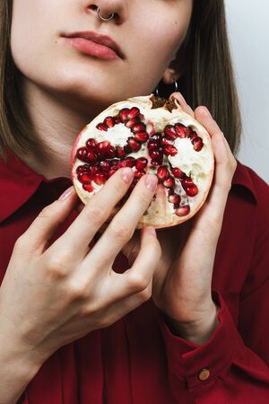 Faceless portrait of woman's hands holding half of pomegranateの写真素材