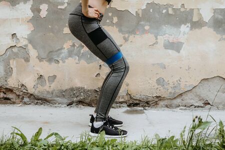 Faceless portrait of young adult female exercising outdoors in front of rustic wallの写真素材