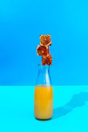 Stack of cubes made of red oranges on the glass bottle with citrus juice, selective focusの写真素材