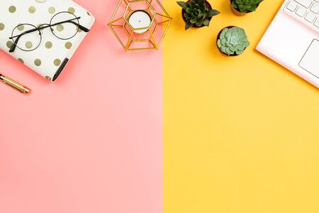 Business feminine mockup with smartphone pink laptop, succulent flowers, glasses, pen, planner and candle, pastel pink and yellow background. Copyspaceの写真素材