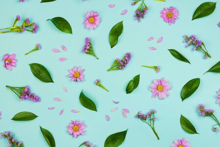 Flatlay floral background with daisies, wildflowers, petals and leaves, blue background.の写真素材