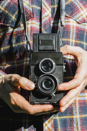 Closeup of man's hands holding vintage two-lens film camera, selective focus
