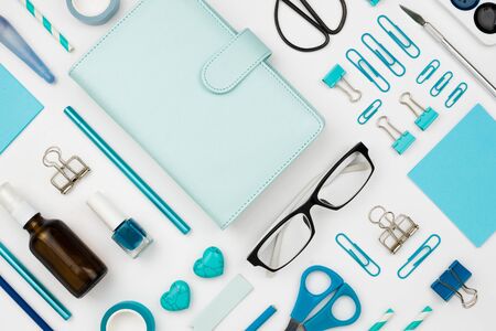 Various blue stationary and office tools and accessories knolled together on white: planner, pens, pencils, clips, glasses, scissors, etc. Flatlayの写真素材