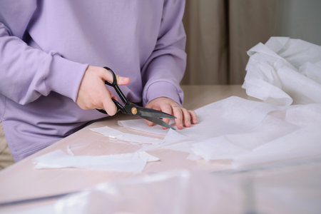 Closeup of female tailor cuting out paper sewing patterns in her workshopの写真素材