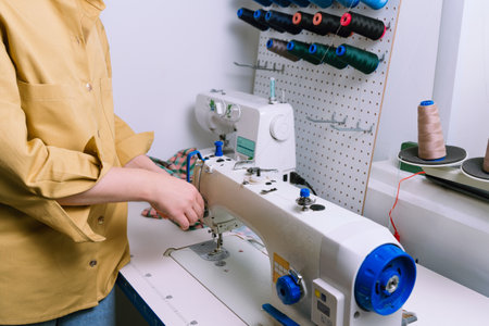 Faceless shot of woman adjusting sewing machine before work in sewing workshopの写真素材