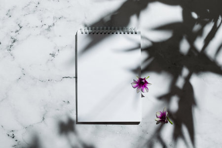 Flatlay of notebook with blank page and orchid flowers on marbleの写真素材