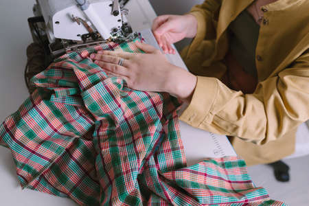 Top view of woman working on overlock sewing machine in her workshop,の写真素材