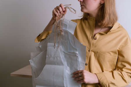 Female in yellow shirt holding paper dress patterns in her workshopの写真素材