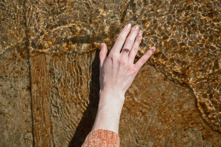 Womans hand in the cold water on a pierの写真素材