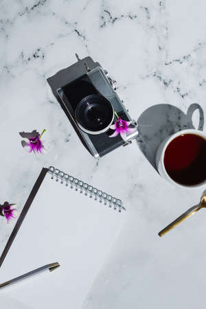 Flatlay of vintage film camera and notebook with pen on marbleの写真素材